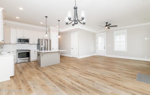 kitchen with stainless steel appliances, a kitchen island, a sink, ornamental molding, and decorative backsplash