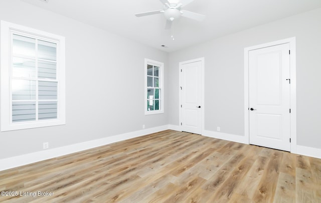 unfurnished bedroom featuring multiple closets, baseboards, visible vents, and light wood finished floors