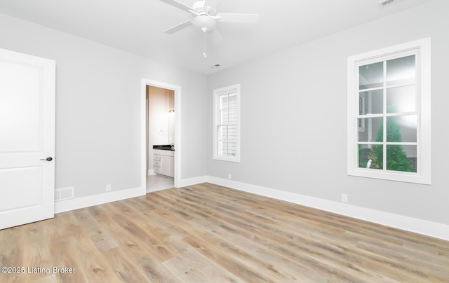 unfurnished bedroom with light wood-style flooring, visible vents, a ceiling fan, baseboards, and ensuite bath