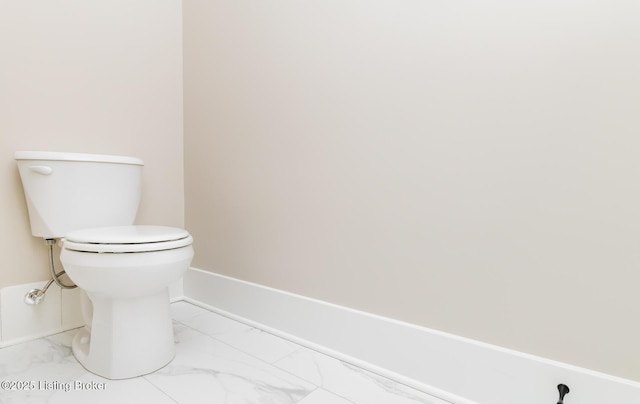 bathroom with marble finish floor, baseboards, and toilet