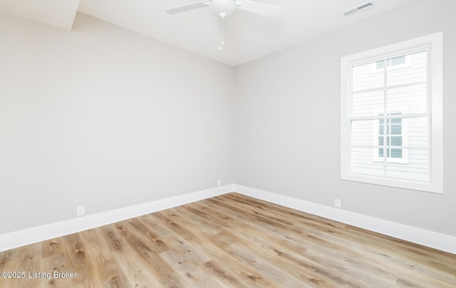 unfurnished room featuring baseboards, visible vents, and wood finished floors