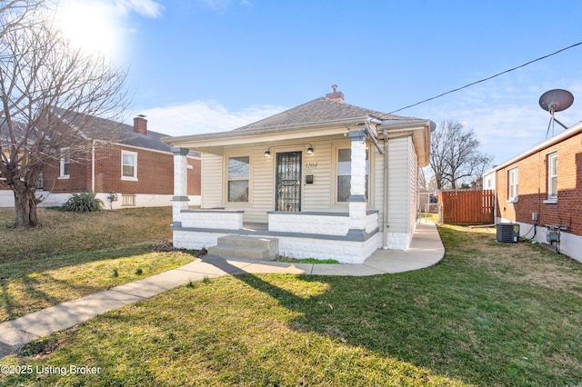 view of front of property featuring a front lawn, a porch, fence, cooling unit, and roof with shingles