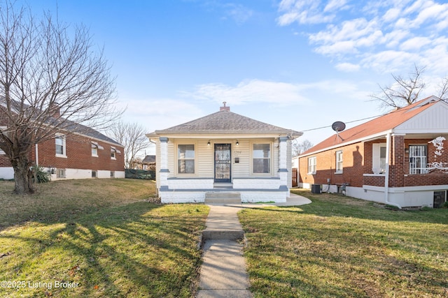 bungalow-style house with cooling unit, a porch, a shingled roof, a chimney, and a front lawn