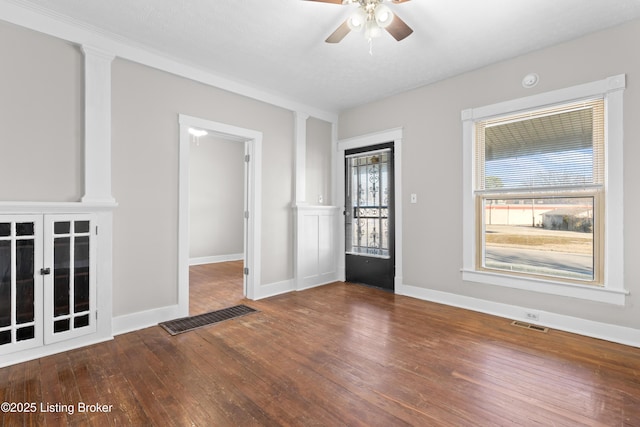 interior space with a ceiling fan, hardwood / wood-style flooring, baseboards, and visible vents