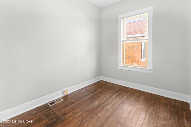 spare room featuring visible vents, baseboards, and dark wood-style floors