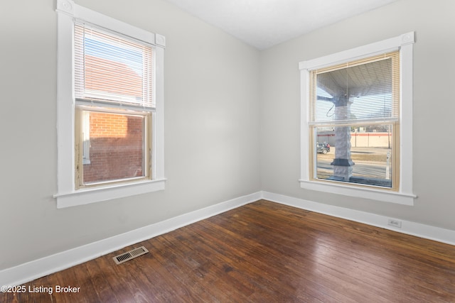 unfurnished room with visible vents, baseboards, and hardwood / wood-style floors