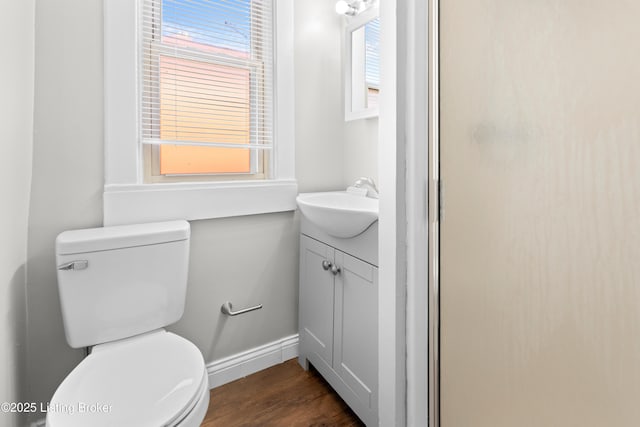 bathroom with vanity, toilet, wood finished floors, and baseboards