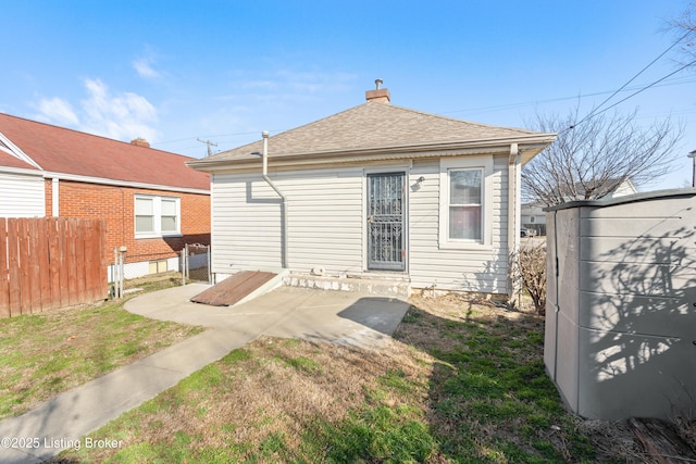 back of property featuring a shingled roof, fence, a chimney, a yard, and a patio area