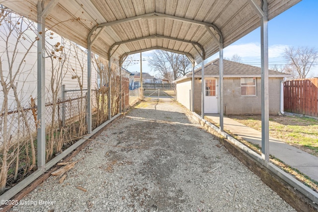 view of parking with a detached carport, driveway, and fence