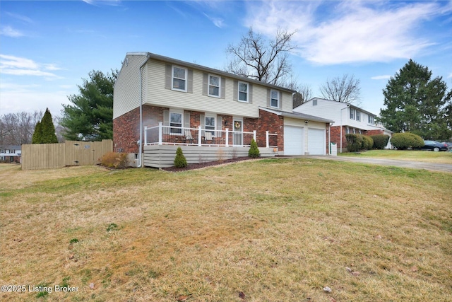 colonial-style house with a front yard, fence, an attached garage, aphalt driveway, and brick siding