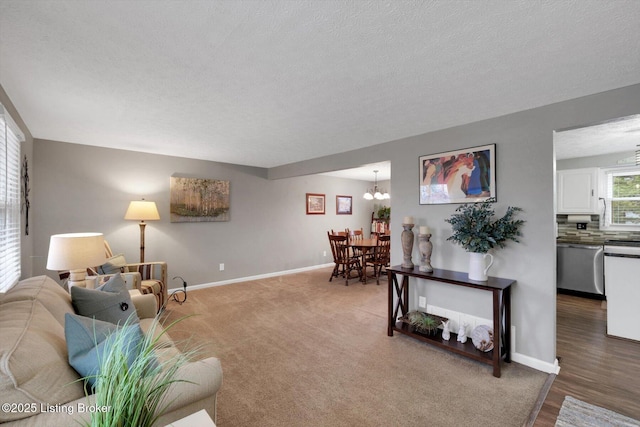 carpeted living area featuring baseboards, a textured ceiling, and an inviting chandelier