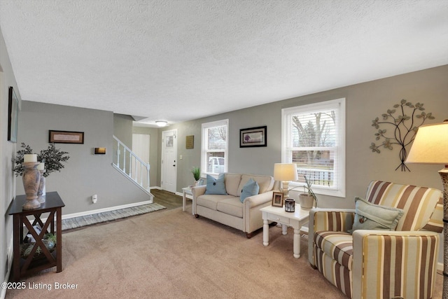 living area with stairs, baseboards, carpet floors, and a textured ceiling