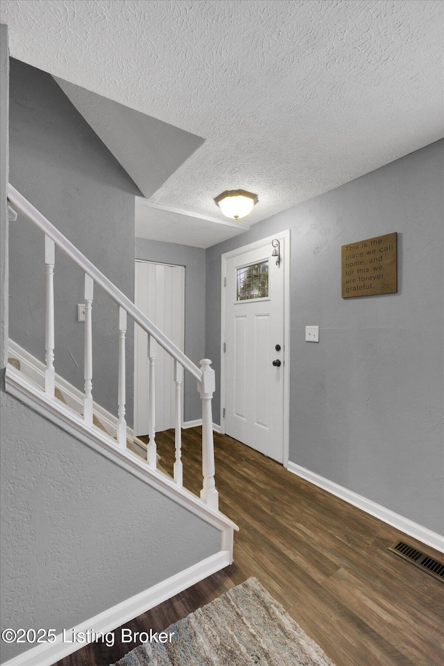 entrance foyer featuring stairway, baseboards, visible vents, and wood finished floors