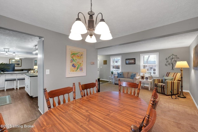 dining area with a notable chandelier, dark wood-style floors, baseboards, and a textured ceiling