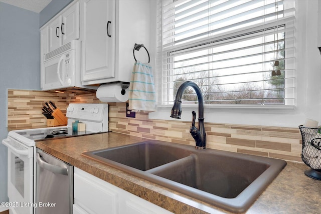 kitchen with a sink, backsplash, dark countertops, white appliances, and white cabinets