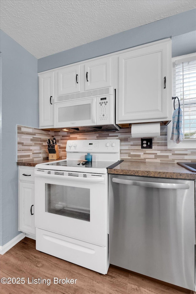 kitchen with decorative backsplash, white appliances, and white cabinets