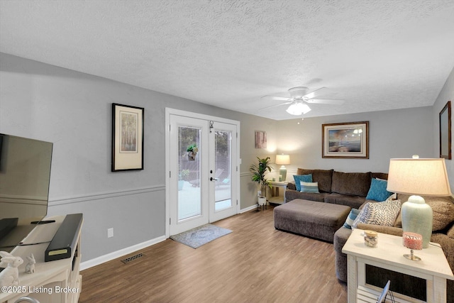 living area featuring wood finished floors, baseboards, visible vents, french doors, and a textured ceiling