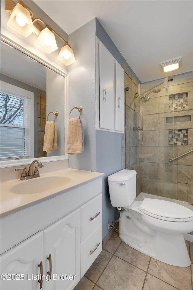 bathroom with vanity, visible vents, a tile shower, tile patterned floors, and toilet