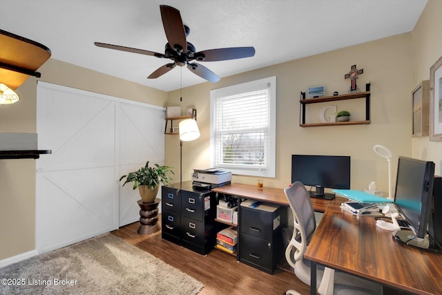 office featuring a ceiling fan, a barn door, and wood finished floors