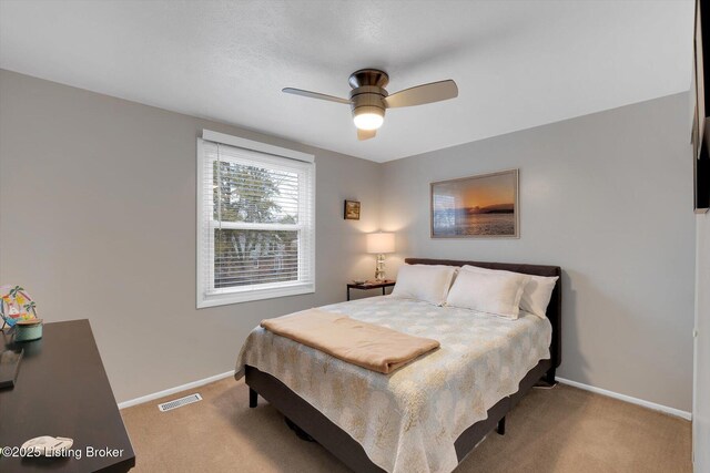 bedroom with visible vents, baseboards, light colored carpet, and ceiling fan