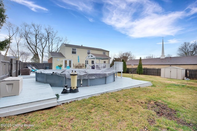 rear view of house with a shed, a lawn, a wooden deck, and a fenced backyard