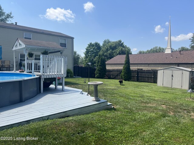 view of yard featuring an outbuilding, a fenced backyard, a storage shed, a wooden deck, and a fenced in pool