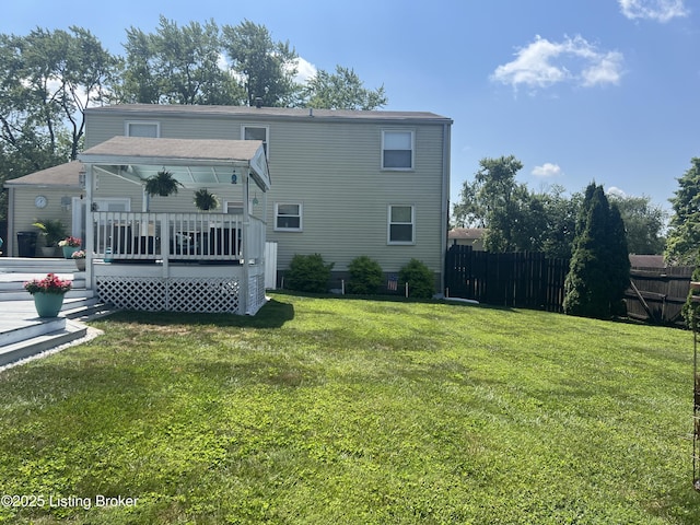 rear view of property with a deck, a yard, and fence