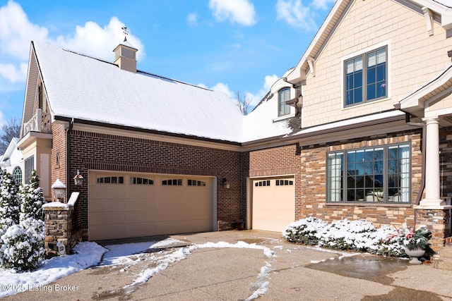 view of front facade with an attached garage, stone siding, a chimney, and brick siding