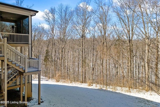 snowy yard featuring a forest view and stairs