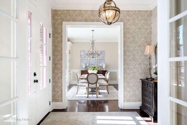 entrance foyer featuring wallpapered walls, crown molding, dark wood finished floors, and a notable chandelier