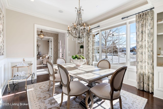 dining room with a decorative wall, dark wood-type flooring, crown molding, and wainscoting