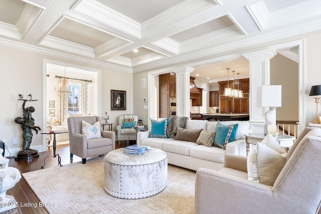 living room featuring a chandelier, beam ceiling, ornate columns, and wood finished floors