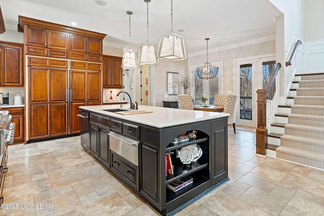 kitchen with decorative light fixtures, crown molding, a warming drawer, light countertops, and a sink