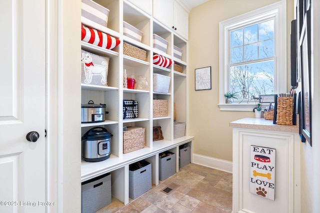 mudroom with stone finish flooring and baseboards