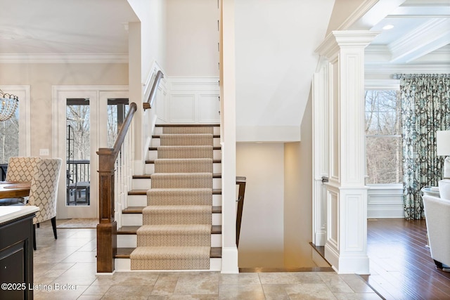 stairway with french doors, ornamental molding, decorative columns, and a decorative wall