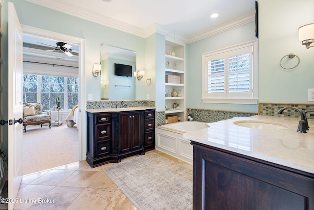 ensuite bathroom with a healthy amount of sunlight, crown molding, and a sink