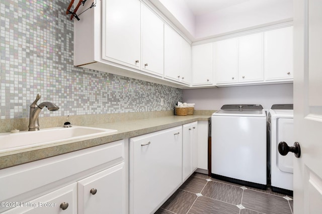 clothes washing area featuring cabinet space, dark tile patterned flooring, a sink, and independent washer and dryer