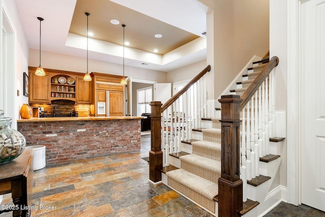 interior space featuring recessed lighting, a raised ceiling, stone tile flooring, and baseboards