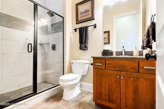 full bathroom featuring vanity, a shower stall, toilet, and baseboards