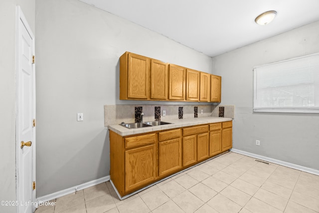 kitchen with light tile patterned floors, visible vents, baseboards, and a sink