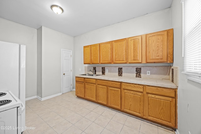 kitchen featuring backsplash, baseboards, light tile patterned floors, white appliances, and a sink