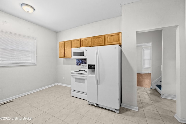 kitchen with visible vents, white appliances, light tile patterned flooring, brown cabinetry, and baseboards