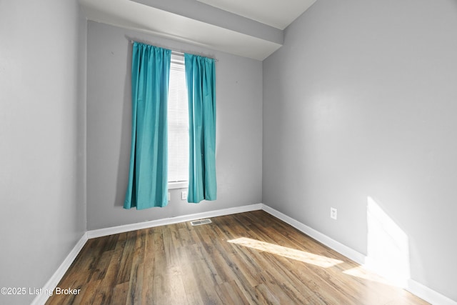 unfurnished room featuring visible vents, a healthy amount of sunlight, baseboards, and wood finished floors