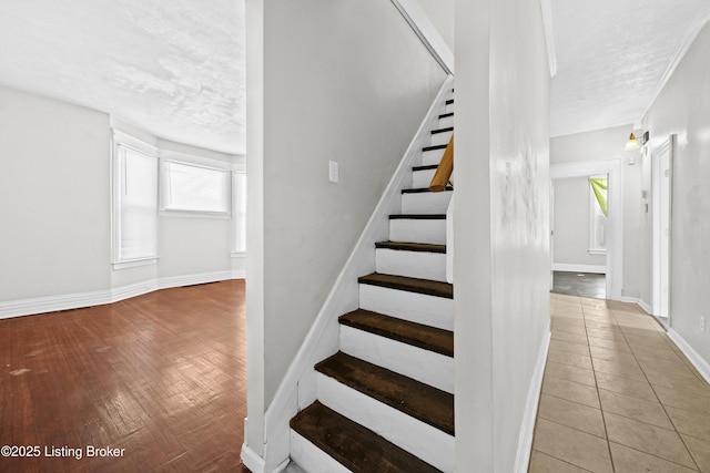 staircase featuring tile patterned flooring, a textured ceiling, and baseboards