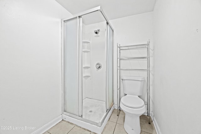 bathroom featuring tile patterned flooring, a stall shower, toilet, and baseboards