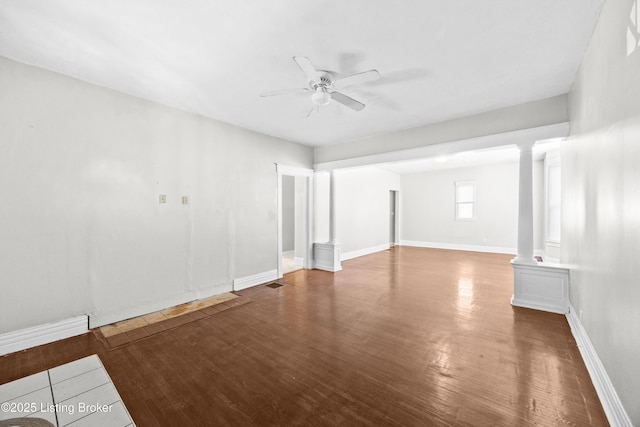 empty room featuring visible vents, wood finished floors, baseboards, ceiling fan, and ornate columns