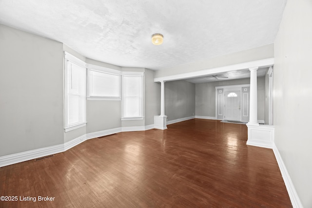 unfurnished living room with visible vents, wood finished floors, ceiling fan, and decorative columns