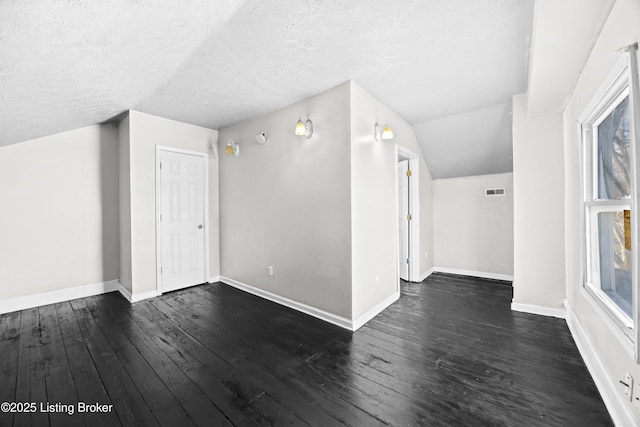 bonus room with baseboards, dark wood-type flooring, and a textured ceiling
