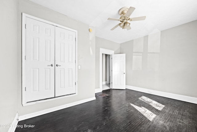 unfurnished bedroom with a closet, baseboards, dark wood finished floors, and a ceiling fan