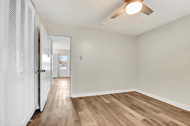 unfurnished room with wood finished floors, a ceiling fan, and baseboards